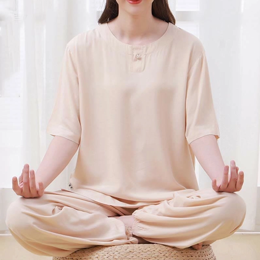 Close-up front view of beige tai chi meditation uniform set showing crew neckline detail and half sleeve on model