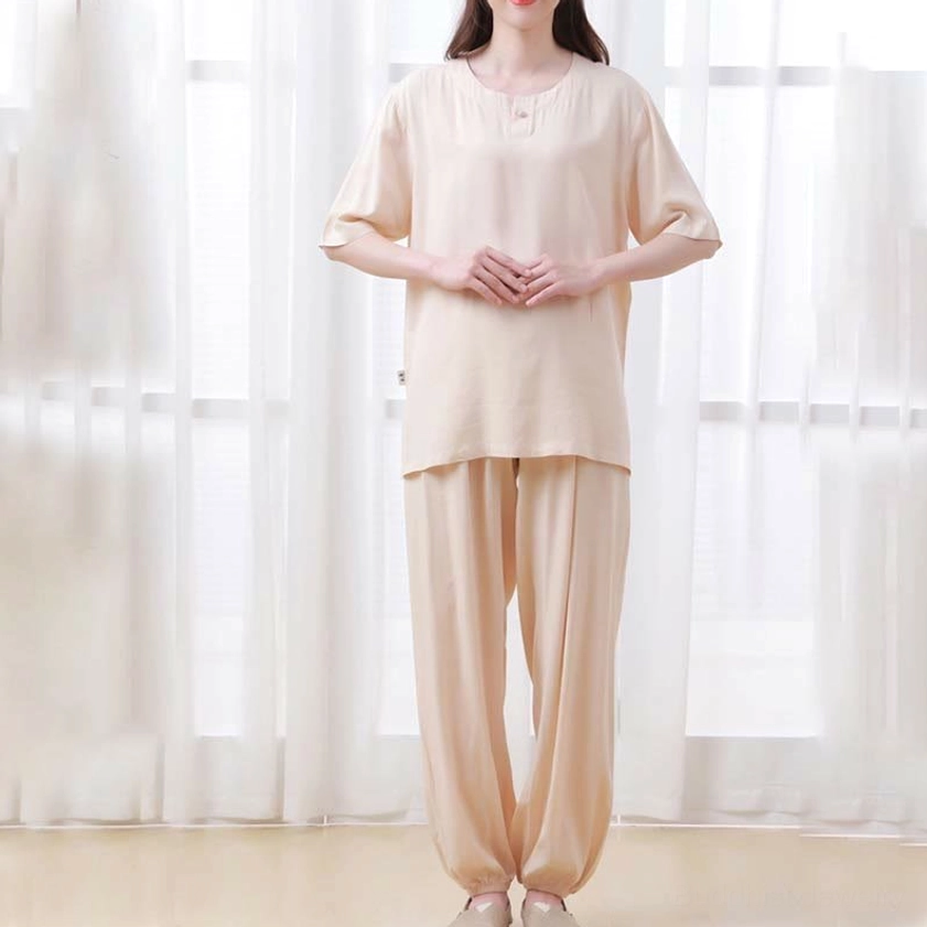 Full front standing view of women's complete beige tai chi meditation outfit with half sleeve top and loose comfortable pants in indoor setting