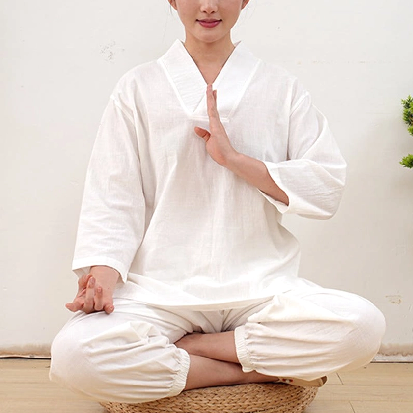 Women in white meditation and tai chi clothing set cross-legged in mindful practice pose