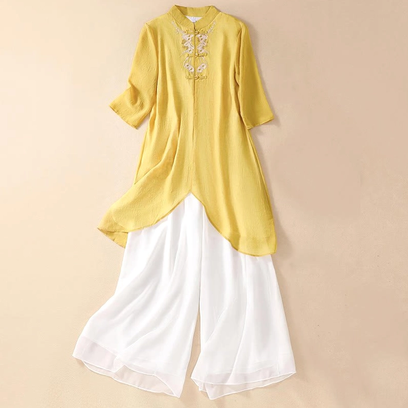 Women's Zen meditation embroidered two-piece set featuring yellow tunic with floral embroidery and white wide leg pants, front flat lay view