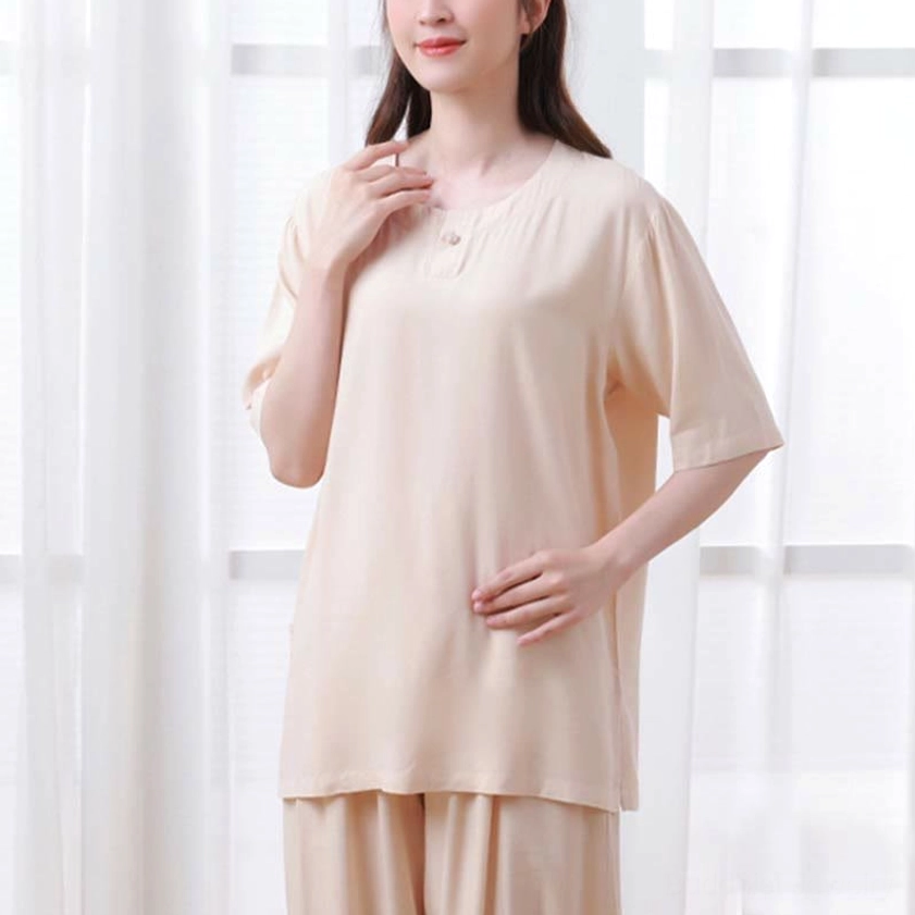 Full front standing view of beige women's zen meditation clothing set in bright indoor setting showing complete outfit and loose fit design