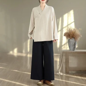 Women's beige zen meditation yoga uniform set with black wide-leg pants, full body front view showcasing v-neck long sleeve top