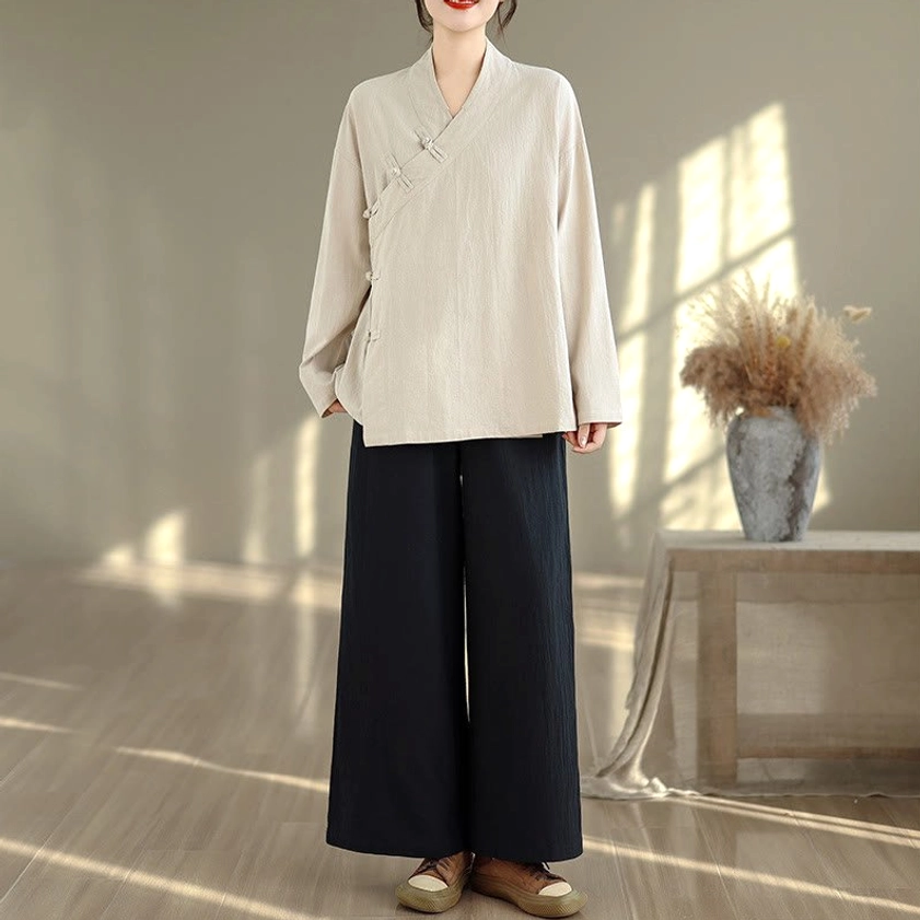 Women's beige zen meditation yoga uniform set with black wide-leg pants, full body front view showcasing v-neck long sleeve top