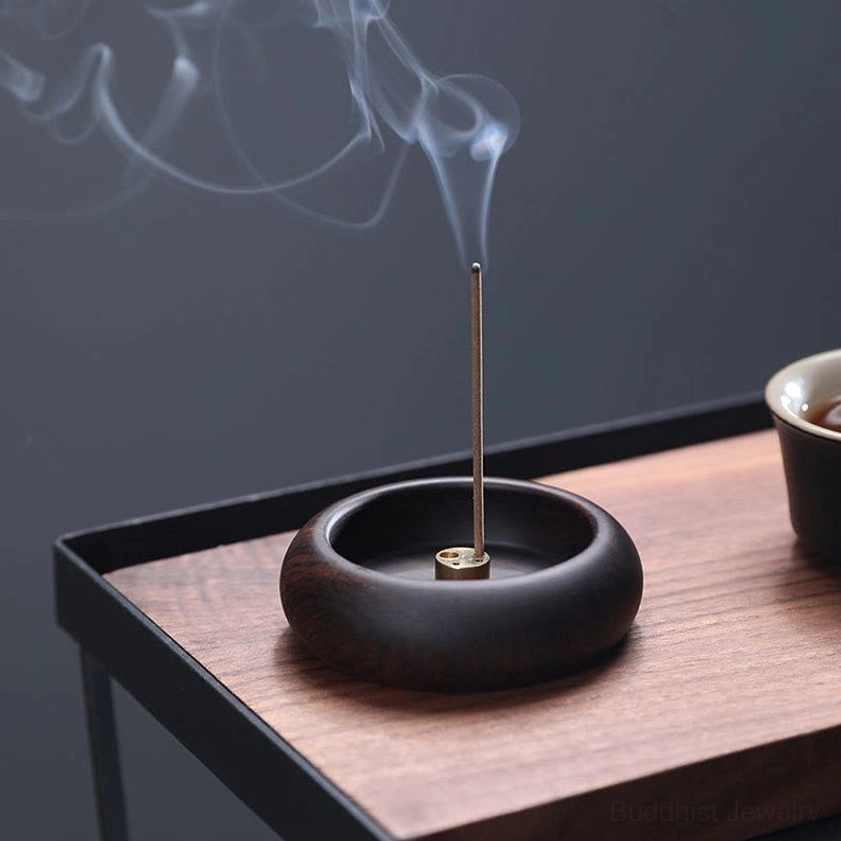 Dark wood handcrafted incense holder with matte finish, smoking incense on minimalist wooden table
