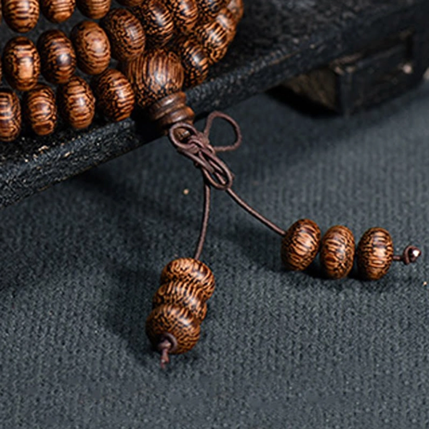 Close-up detail of wooden mala tassel set with disc beads, knotted cord and cylindrical tassel beads