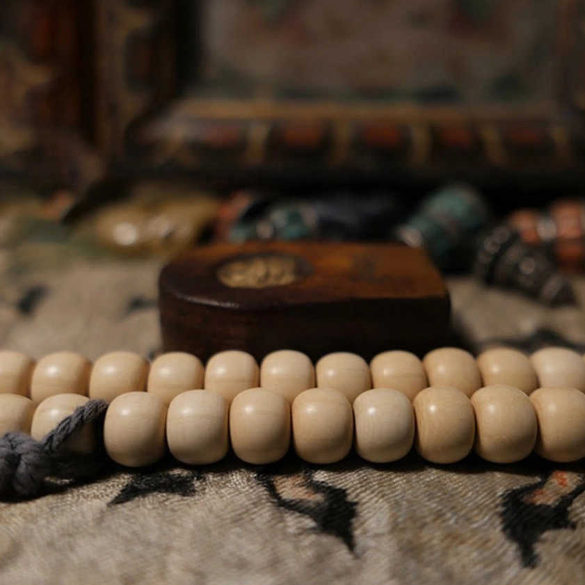 Close-up side view of Abelia Biflora wood mala bracelet showing smooth beige beads and wooden spacer block
