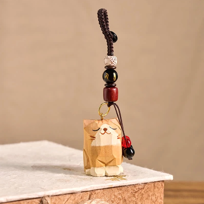 Hand-carved wooden cat Om Mani Padme Hum keychain three-quarter angle with red tassel charm and mantra beads