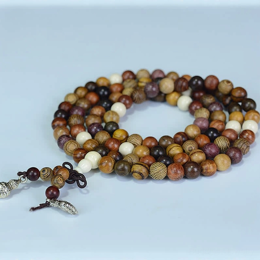 Multi-tone natural wood mala beads looped necklace with silver pendants on light blue background, flat lay top-down view