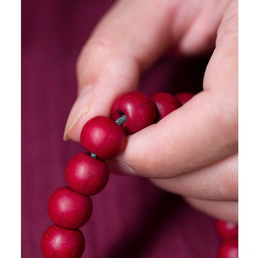 Abelia Biflora wood mala beads held between thumb and forefinger showing round bead texture
