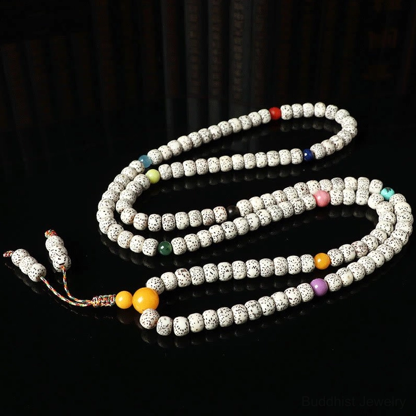 Wrap-around bodhi seed mala with colored spacer beads and braided tassel on dark reflective background