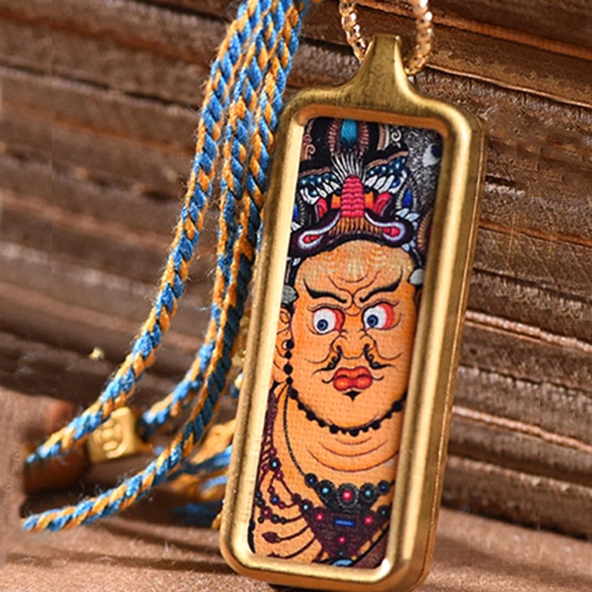 Large framed wealth deity thangka pendant necklace with blue-yellow rope chain and gold metal frame on wood background