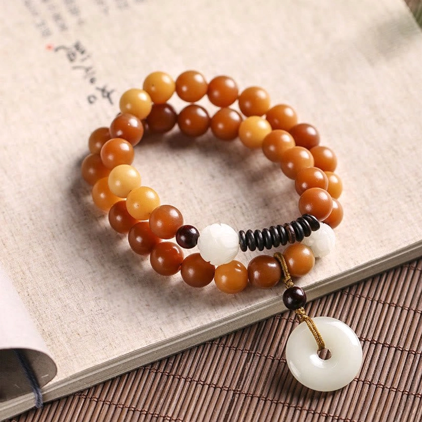 Yellow bodhi seed double wrap bracelet with jade peace buckle pendant showing warm golden-yellow beads and white lotus charm