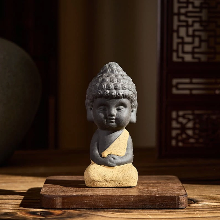 Yellow robed Buddha figurine with hands on abdomen, artisan purple clay contemplative pose