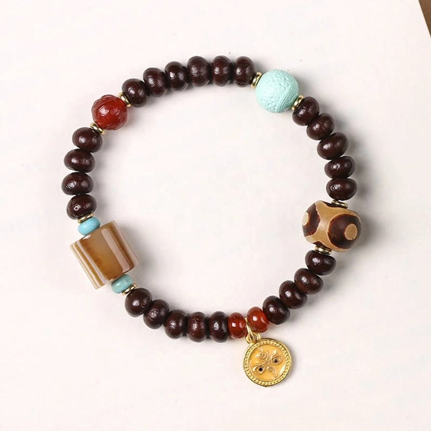 Yellow god of wealth dzi bead bracelet with purple bodhi seeds and gold pendant on white surface