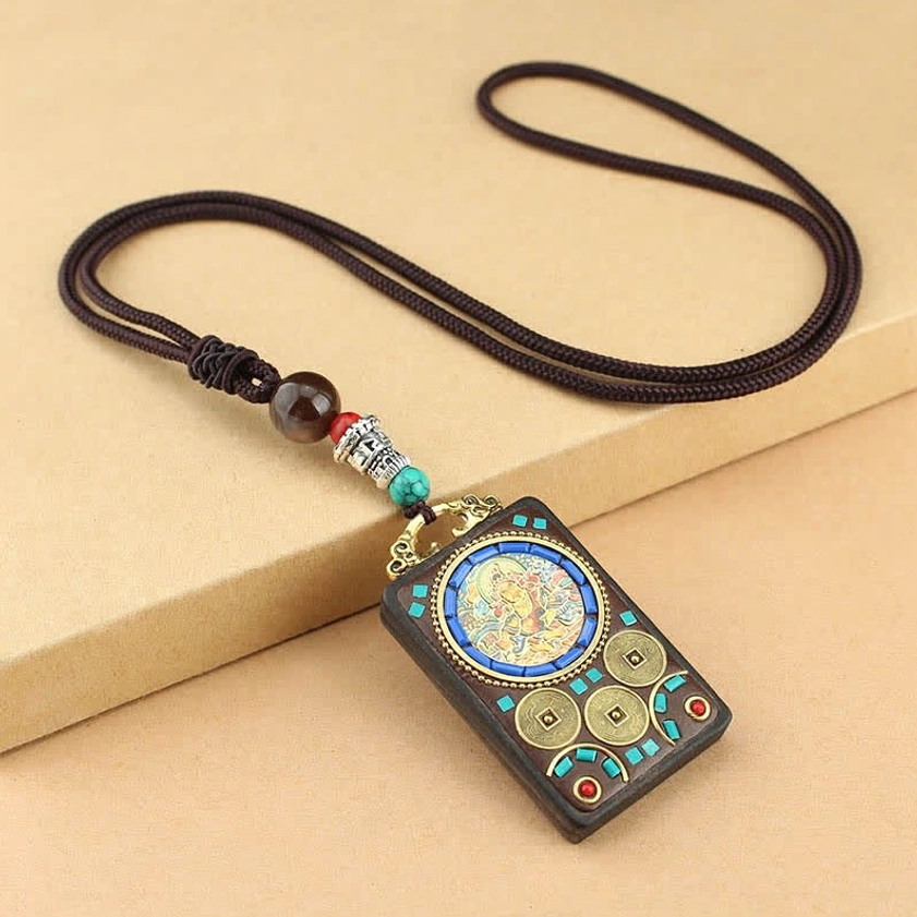 Yellow God of Wealth Thangka ebony wood necklace pendant, close-up overhead view showing round central deity pattern with turquoise inlays
