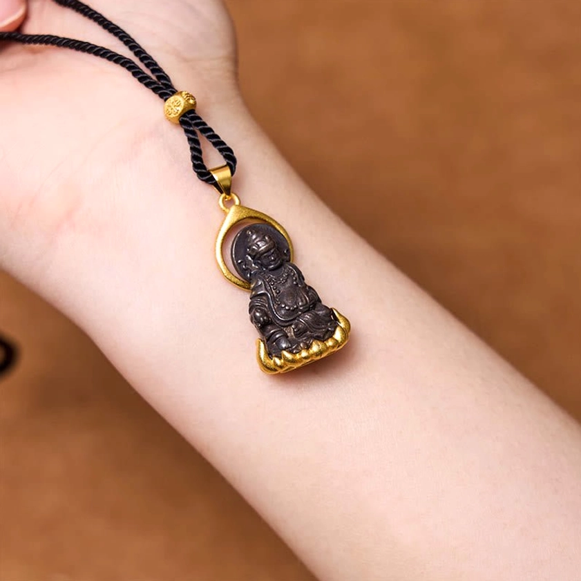 Buddhist Jambhala pendant necklace worn on wrist showing gold decorative bead and ornate lotus base detail