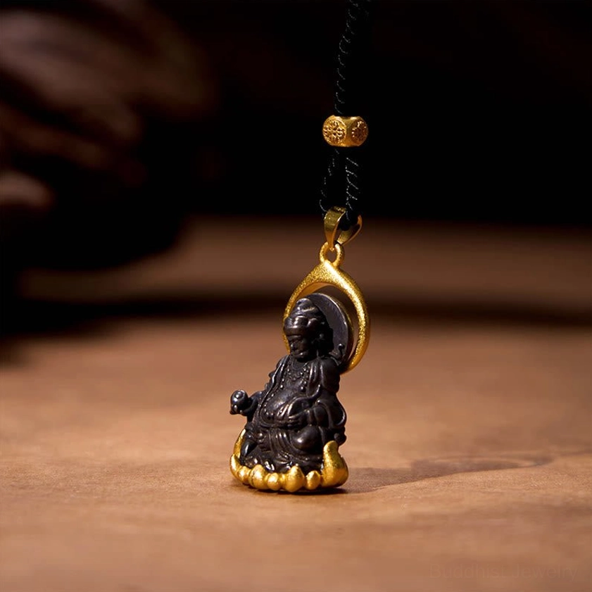 Yellow Jambhala wealth god pendant with gold halo and lotus-shaped base on wooden surface close-up
