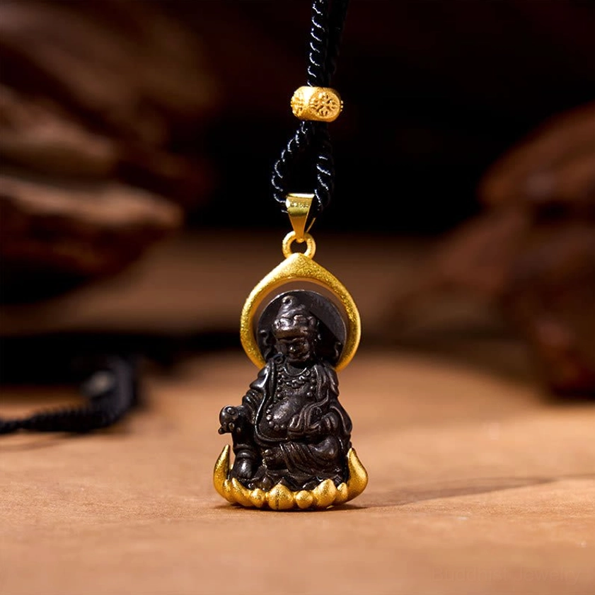 Yellow Jambhala Buddha wealth pendant necklace with black braided cord and gold-tone metal frame on wooden background