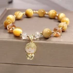 Yellow tiger eye meditation Buddha protection bracelet with gilded Buddha pendant on gray jewelry box