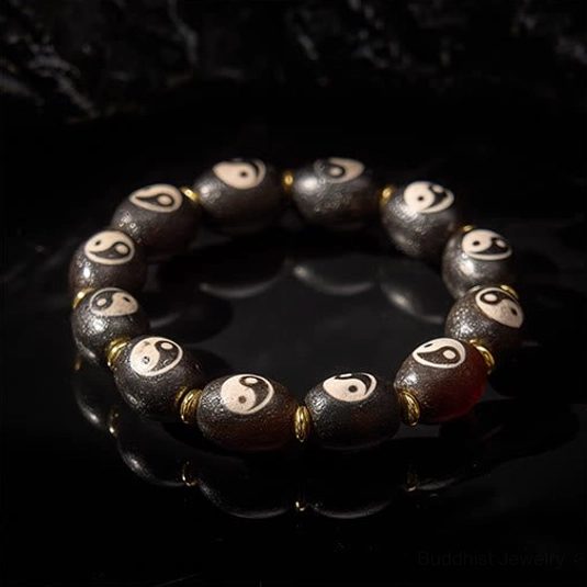 Yin yang agate dzi beads close-up on reflective dark background showing bead texture and yin yang symbol details