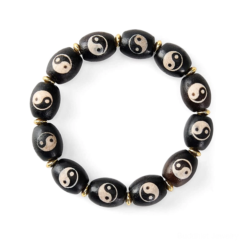 Yin yang agate dzi bead bracelet on white background flat lay showing black beads with yin yang symbols and gold accents