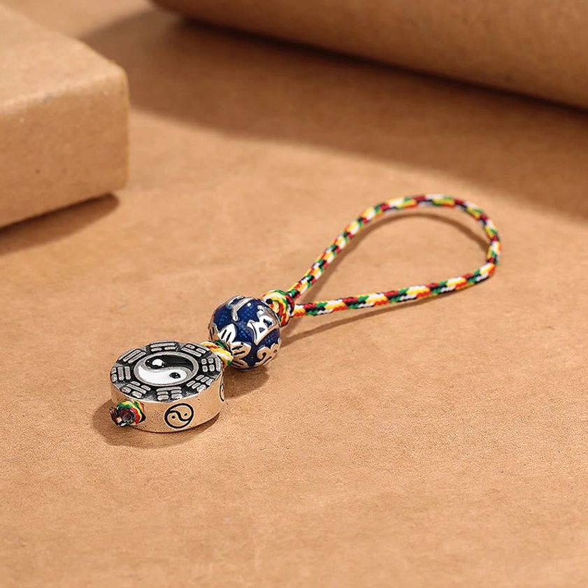 Overhead view of spiritual copper keychain displaying dual-sided Bagua Yin Yang pendant with colorful braided strap
