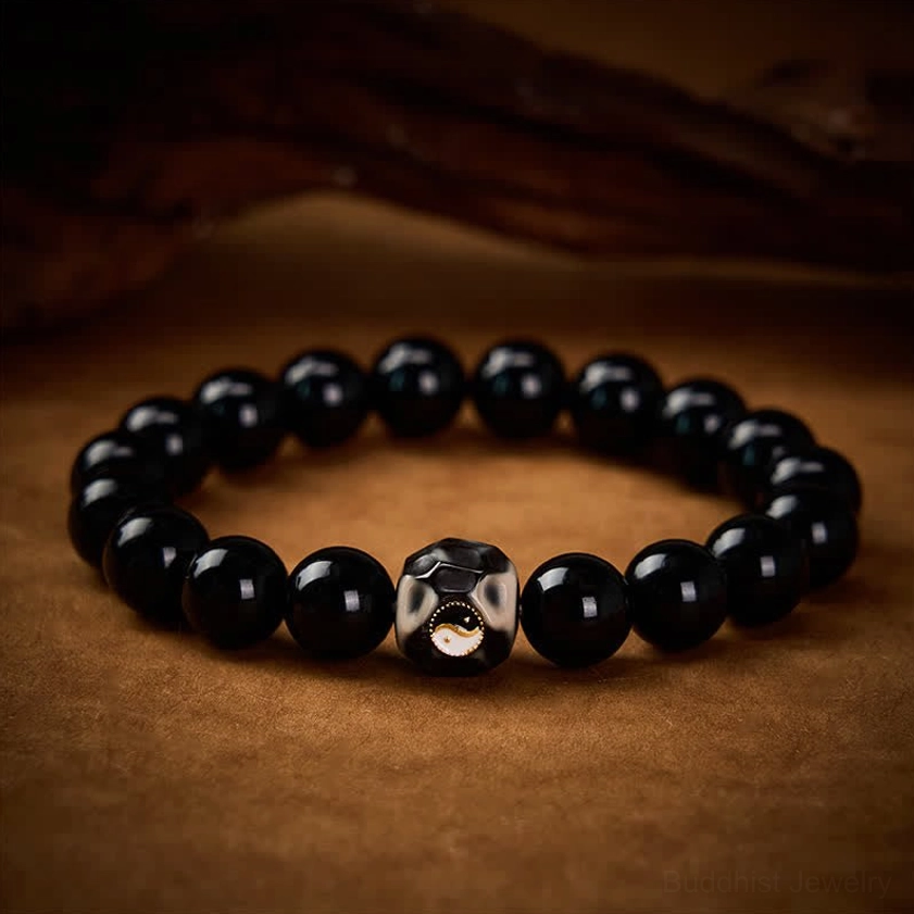 Spiritual Yin Yang balance bracelet with smooth black obsidian beads and detailed centerpiece on wooden surface