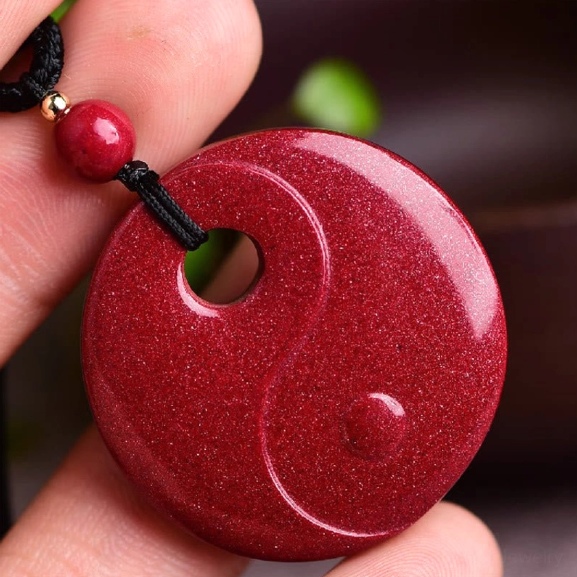 Yin Yang cinnabar Buddhist necklace pendant held in hand showing shiny deep red finish and round carving details