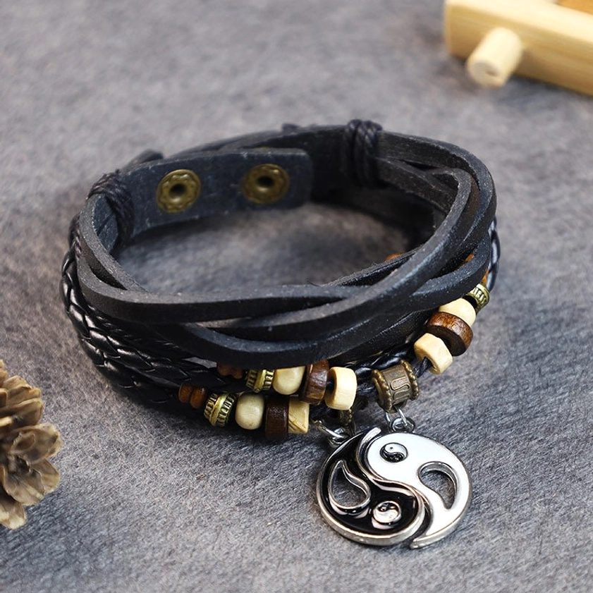 Yin yang balance couple bracelet with copper charm pendant, layered black leather, mixed beads, and snap closure displayed in top-down flat lay