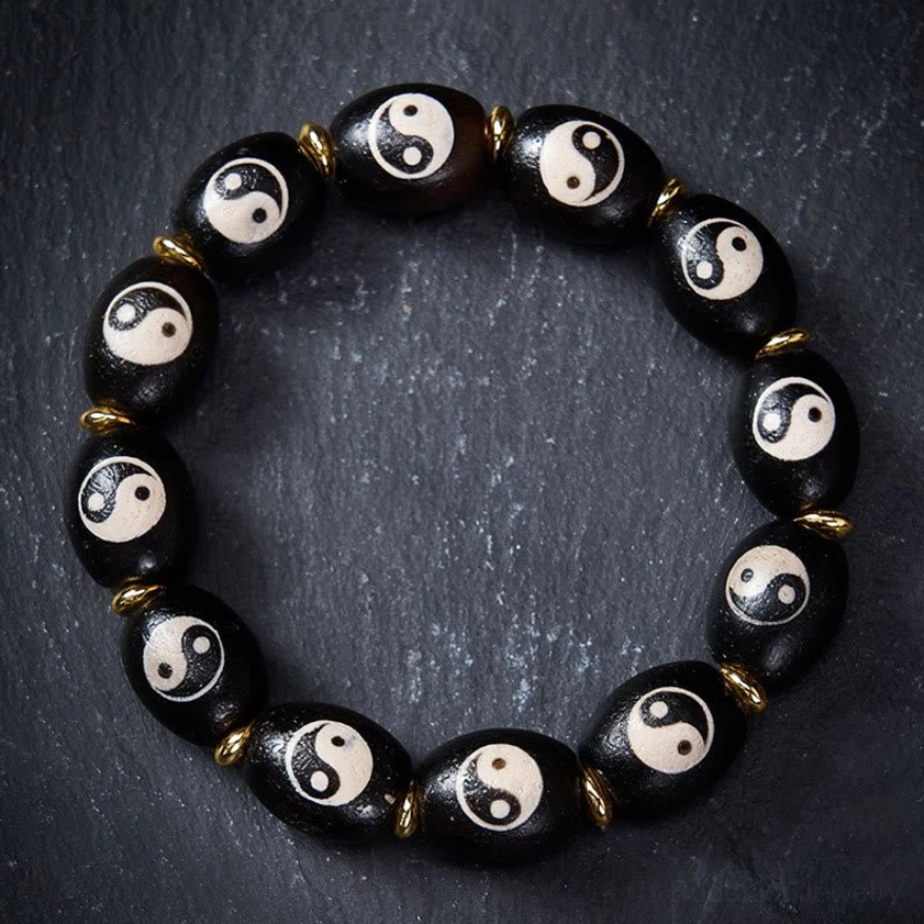 Yin Yang agate dzi bead bracelet flat lay overhead view on grey background showing hand-painted yin yang patterns