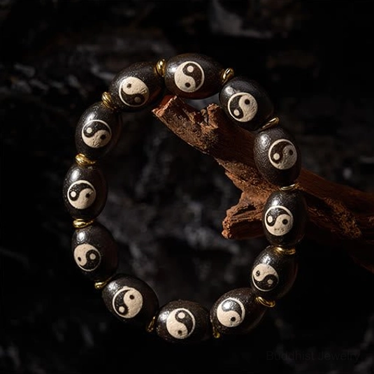 Yin yang dzi bead bracelet side view on natural wood and rock background displaying protective amulet craftsmanship