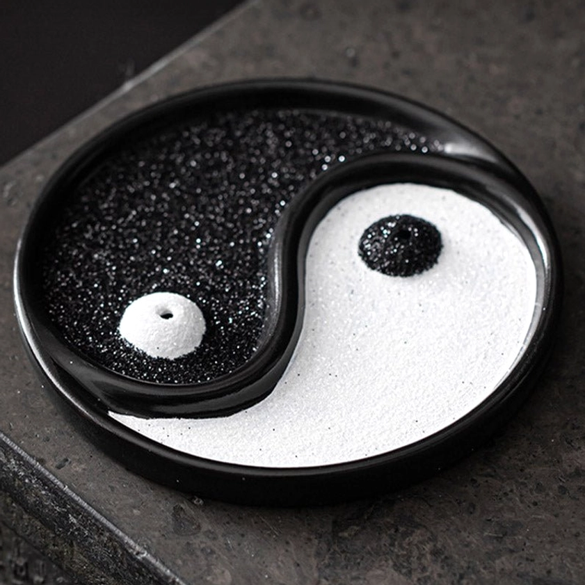 Yin Yang incense holder overhead close-up on dark stone tabletop showing full yin yang pattern and incense placement holes
