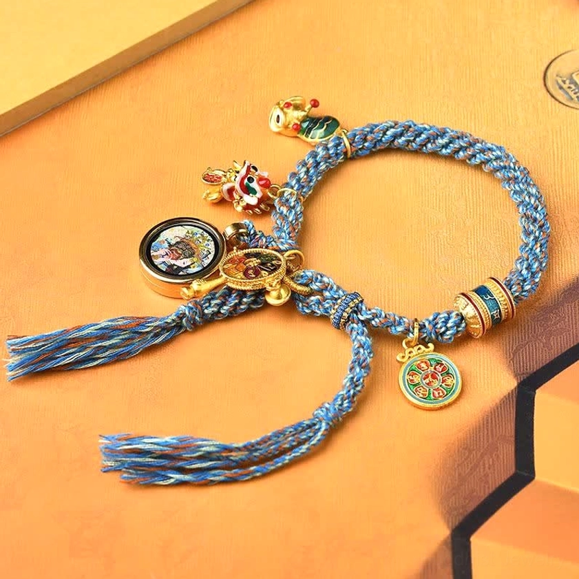 Zakiram Goddess of Wealth Buddhist bracelet showing braided blue rope with multiple ethnic metal charms in side view