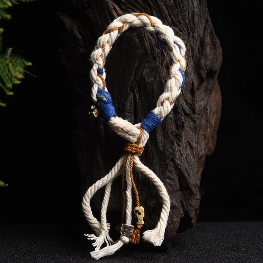 Braided lucky string bracelet in flat lay featuring white tan and blue woven design with blue binding sections and decorative pendants