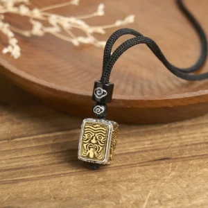 Zakiram goddess square pendant necklace with dual-tone metal finish and black braided rope, top-down view on wooden tray