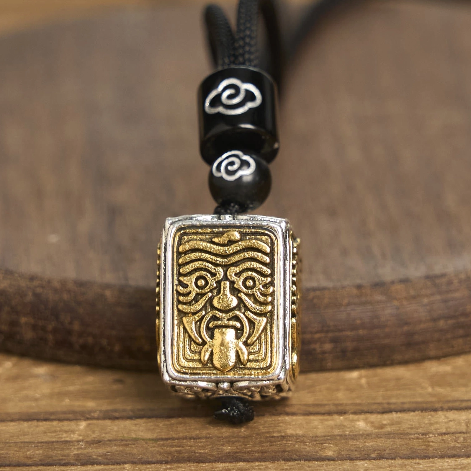 Square Buddhist pendant with fierce guardian deity relief and protruding tongue, protective symbol close-up