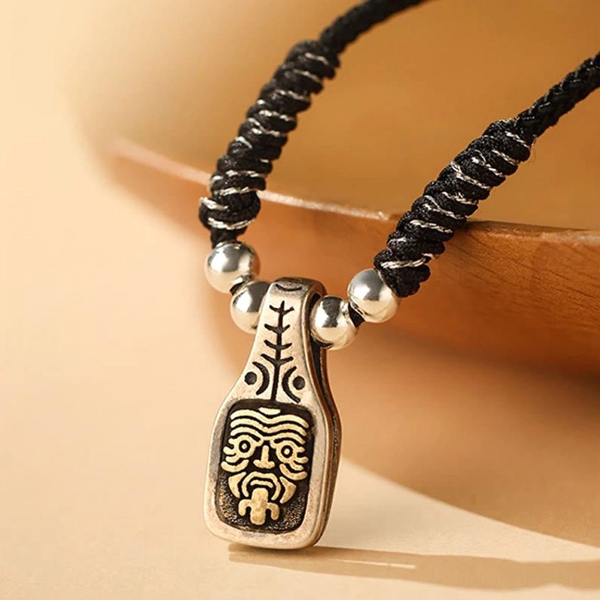 Close-up of Zakiram goddess pendant with hand-engraved face and silver beads on black cord