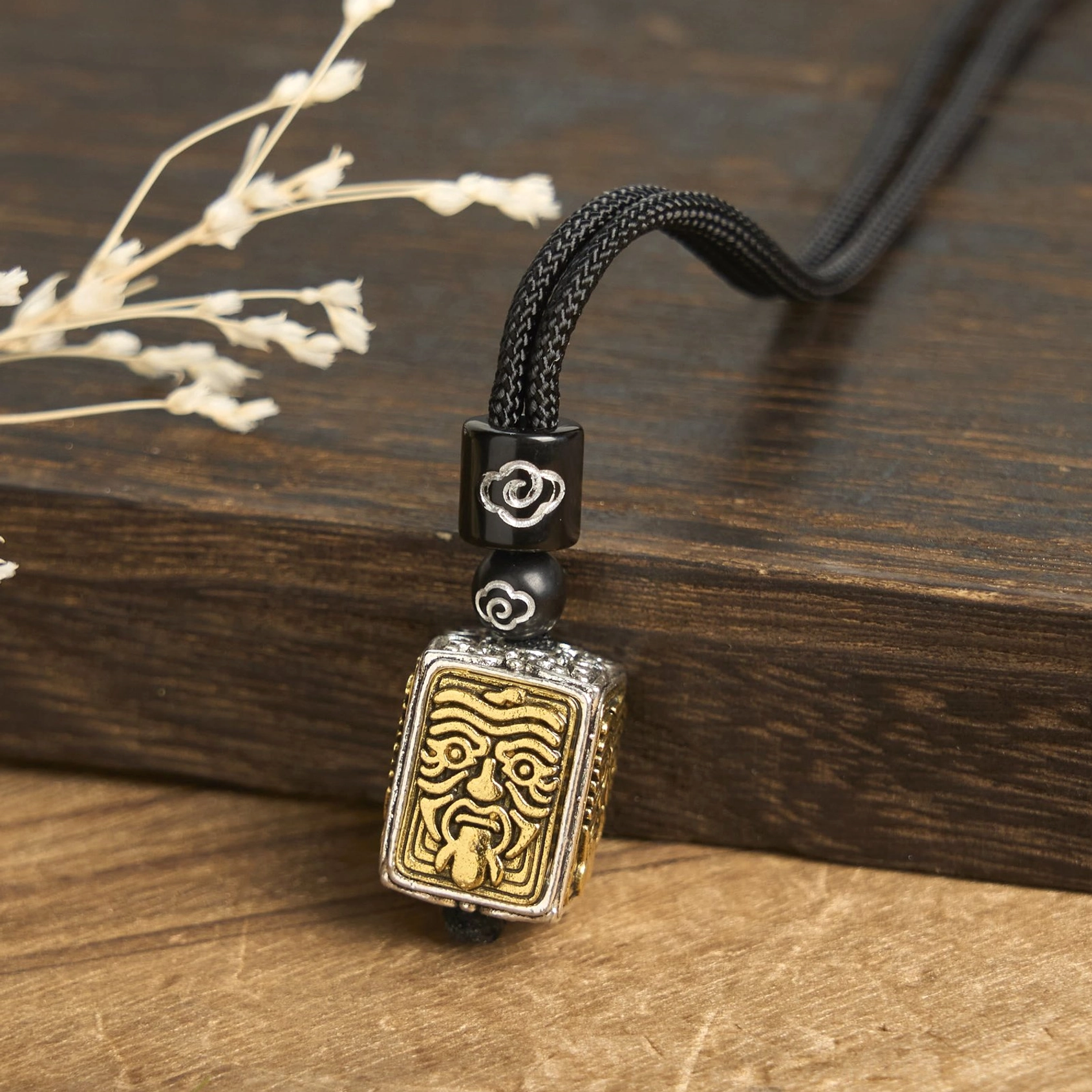 Handcrafted Zakiram protection necklace pendant on wooden surface with dried flowers, side view