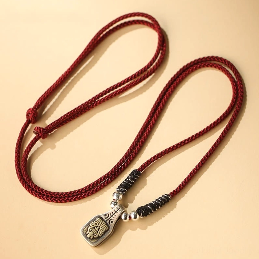 Red braided Zakiram goddess necklace with black cord and hand-engraved silver pendant close-up detail