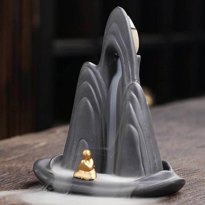 Zen backflow incense holder with visible smoke flow and meditation monk figurine - right side view