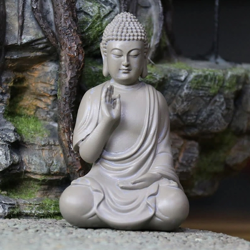 Zen Buddha desk ornament displayed on table with rockery landscape background, resin statue matching zen garden meditation style