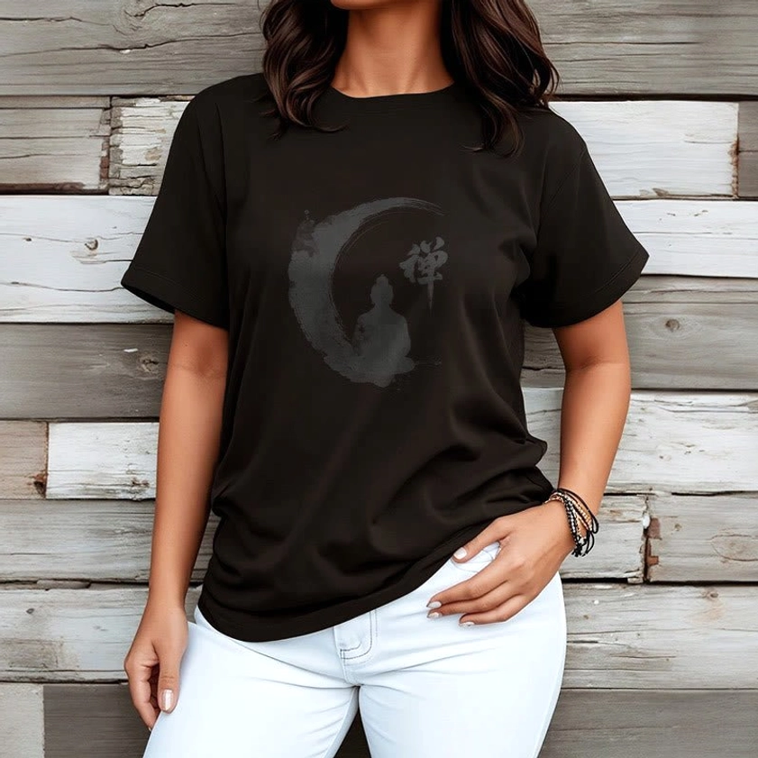 Female model wearing black Zen Buddha meditation t-shirt with white slim-fit jeans on wooden plank backdrop, showcasing versatile styling of the Buddhist graphic tee