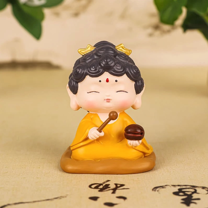 Zen Buddha resin figurine holding wooden meditation tools and prayer mallet on calligraphy desktop