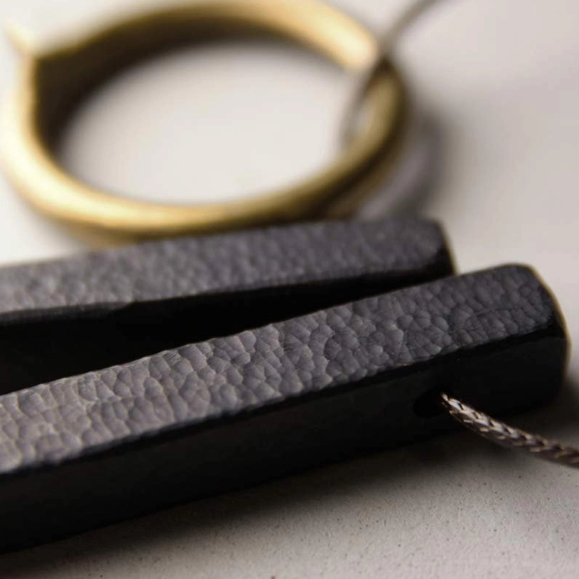 Buddhist Zen circle necklace pendant with waxed cord coiled display on ceramic plate
