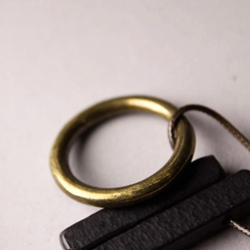 Zen circle Buddhist necklace macro close-up showing black wood texture and brass ring