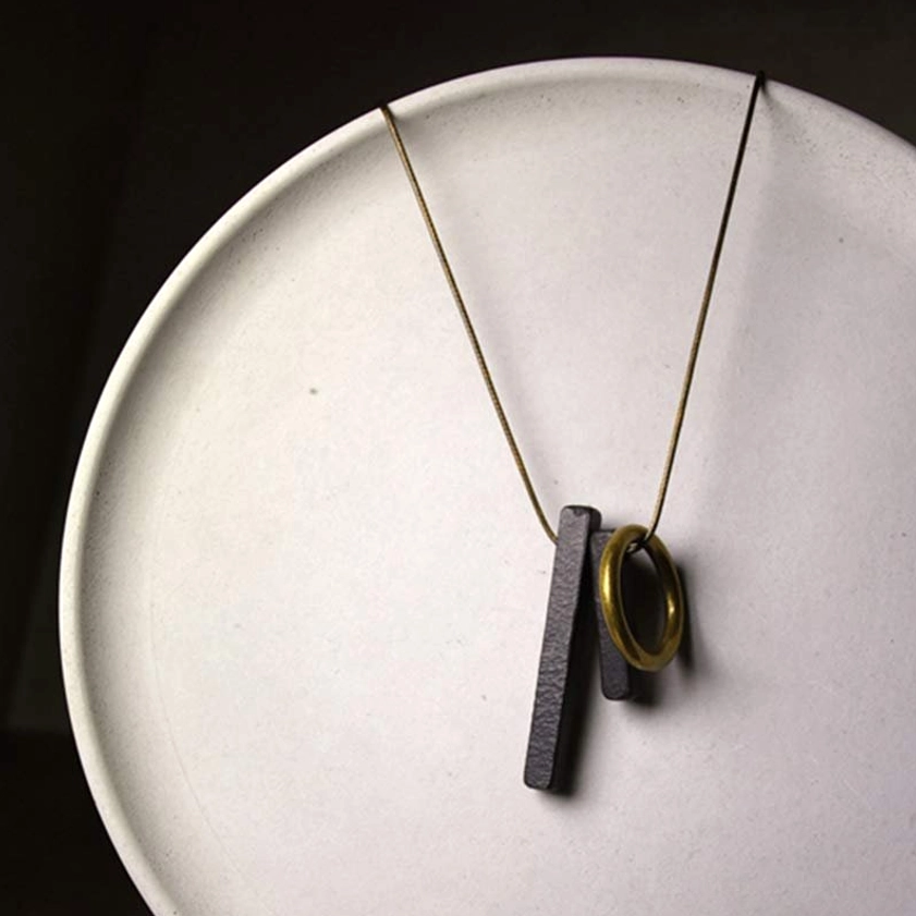 Zen circle Buddhist pendant necklace displayed on white ceramic plate showing detailed craftsmanship
