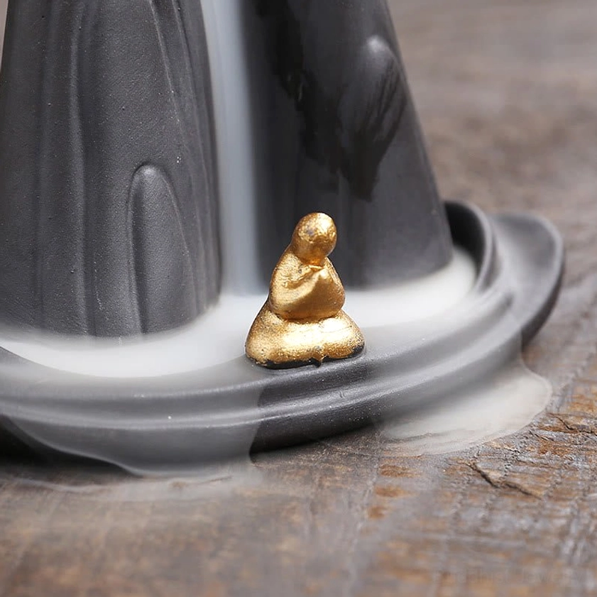 Zen meditation incense burner with flowing smoke waterfall effect and spiritual monk figurine detail