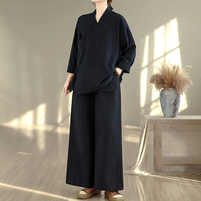 Upper body detail of all-black zen meditation yoga uniform top with v-neck and traditional frog button closure