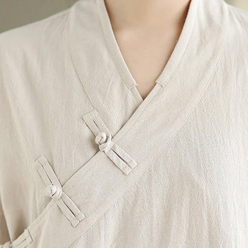 Detailed close-up of zen meditation yoga uniform v-neck cross collar with fabric frog button and wrinkled linen texture