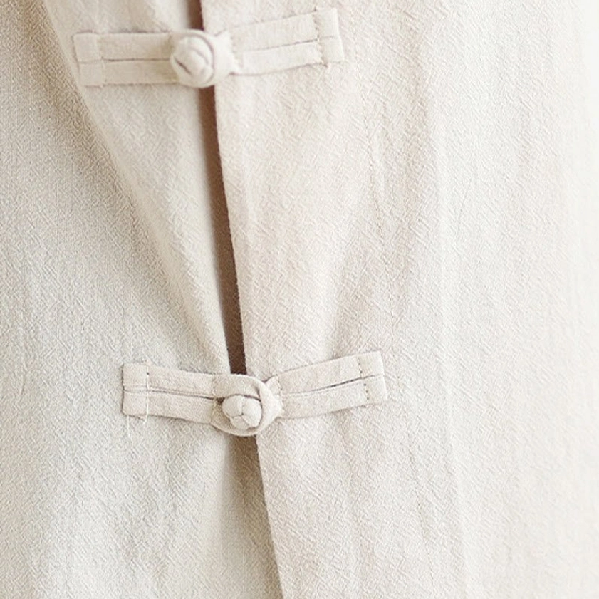 Front close-up of dual fabric frog button closures on women's zen meditation yoga uniform top with plain beige linen